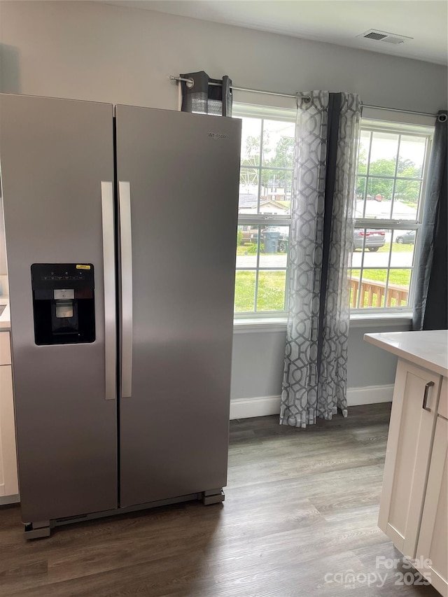 kitchen with stainless steel refrigerator with ice dispenser, visible vents, baseboards, light countertops, and light wood-style floors