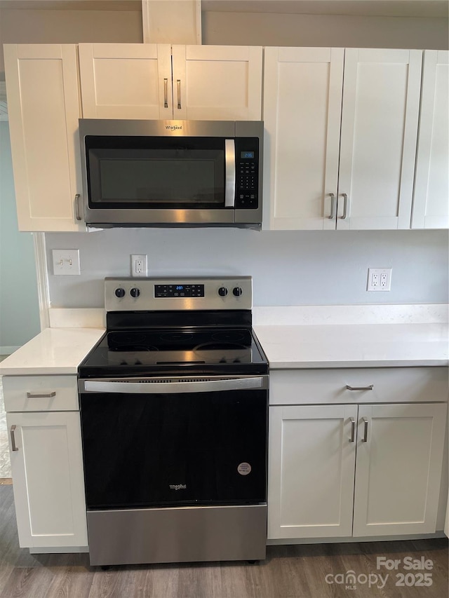 kitchen with light countertops, stainless steel appliances, white cabinets, and wood finished floors