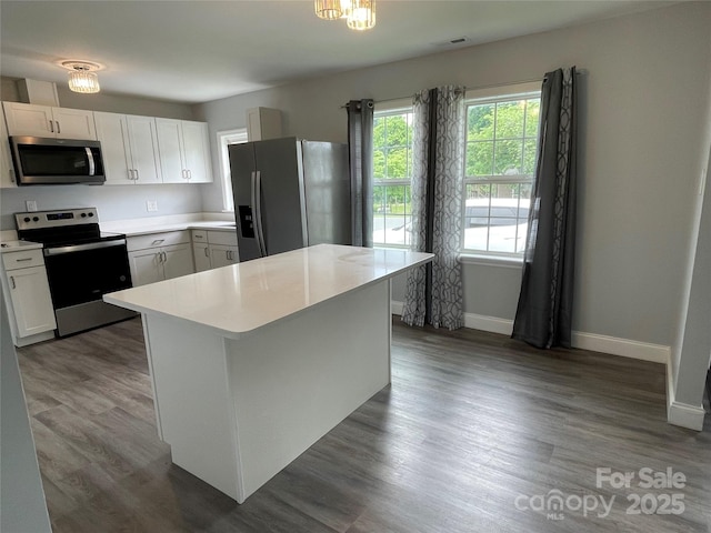 kitchen featuring baseboards, light countertops, stainless steel appliances, and wood finished floors