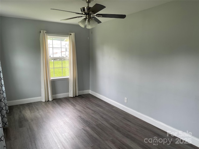 empty room featuring dark wood-style flooring, baseboards, and a ceiling fan