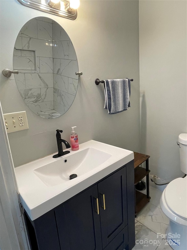 half bath featuring toilet, marble finish floor, and vanity