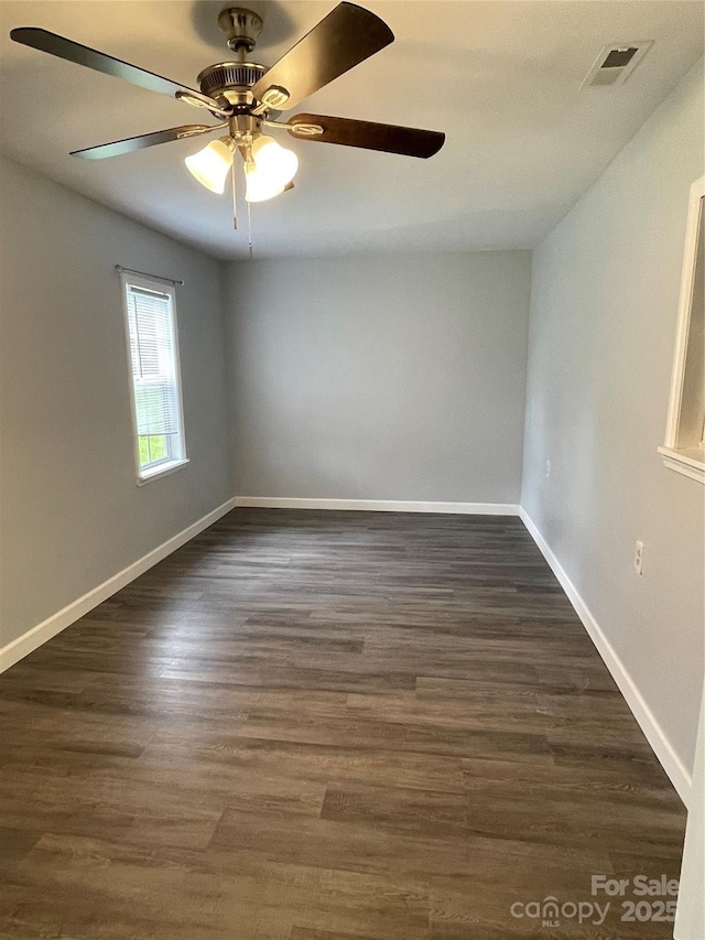 unfurnished room featuring baseboards, ceiling fan, visible vents, and dark wood-style floors