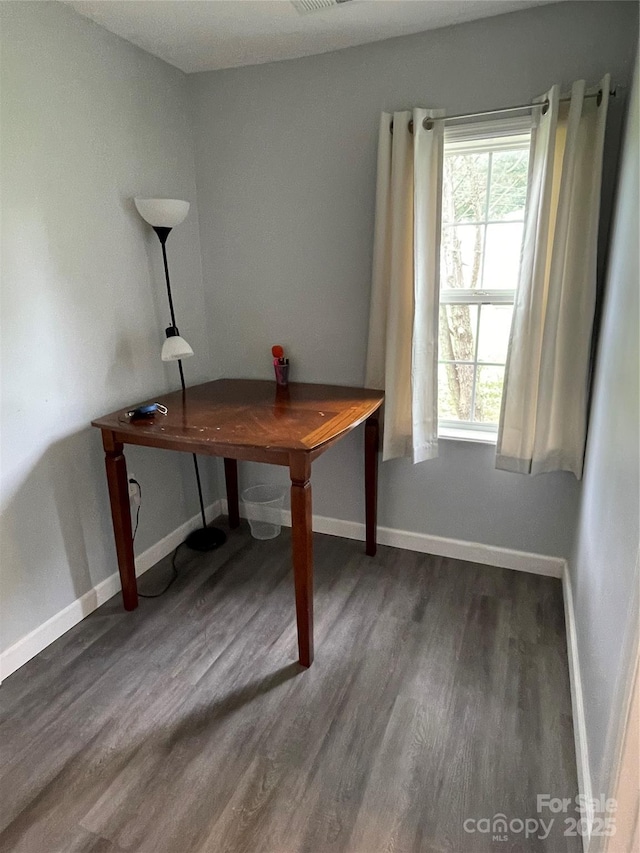 office space with baseboards, visible vents, and wood finished floors