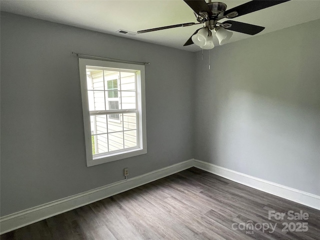 empty room with baseboards, dark wood finished floors, visible vents, and a ceiling fan