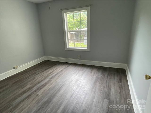 empty room featuring dark wood-type flooring and baseboards