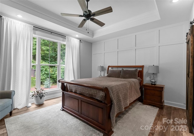 2646 Lee Lawing Rd, Lincolnton, NC 28092 - bedroom featuring a tray ceiling, a barn door, crown molding, wood finished floors, and a decorative wall
