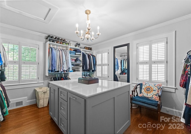 walk in closet with dark wood-style floors, attic access, and a chandelier