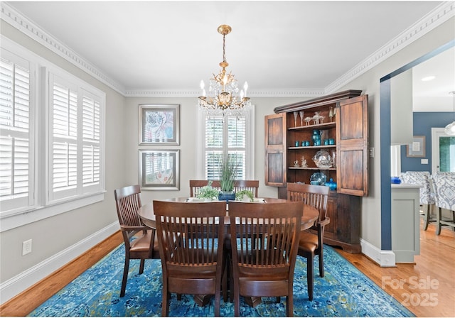 dining space featuring a chandelier, light wood-style flooring, and baseboards