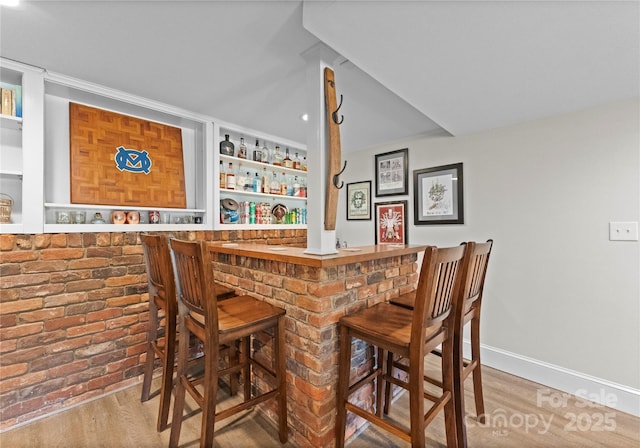 indoor dry bar featuring wood finished floors and baseboards