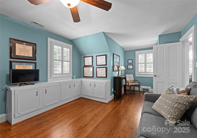living area with ceiling fan, light wood finished floors, baseboards, and vaulted ceiling