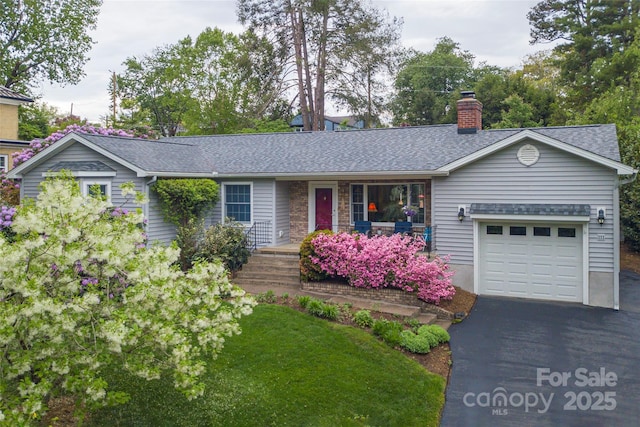 ranch-style home featuring a porch, driveway, a chimney, roof with shingles, and an attached garage