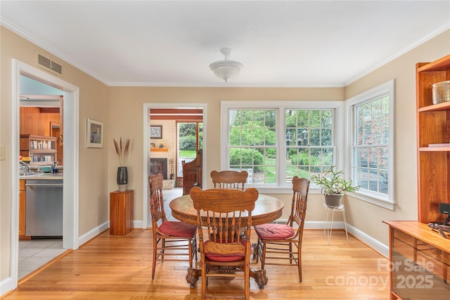 dining space featuring visible vents, ornamental molding, light wood finished floors, and baseboards