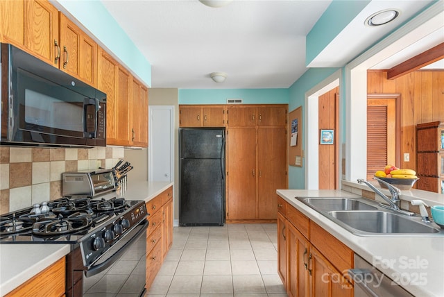 kitchen featuring a sink, light countertops, backsplash, and black appliances