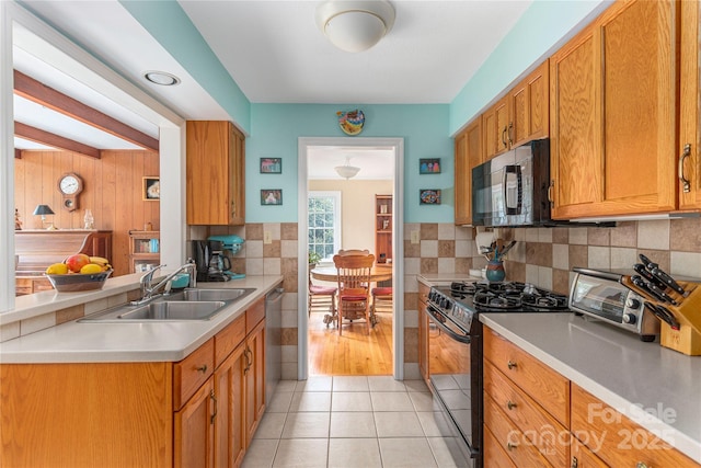 kitchen with a sink, tasteful backsplash, black appliances, and light countertops