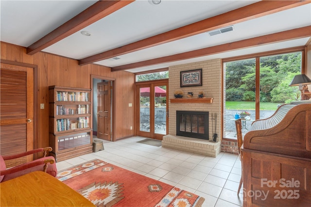living area featuring beamed ceiling, plenty of natural light, and light tile patterned floors