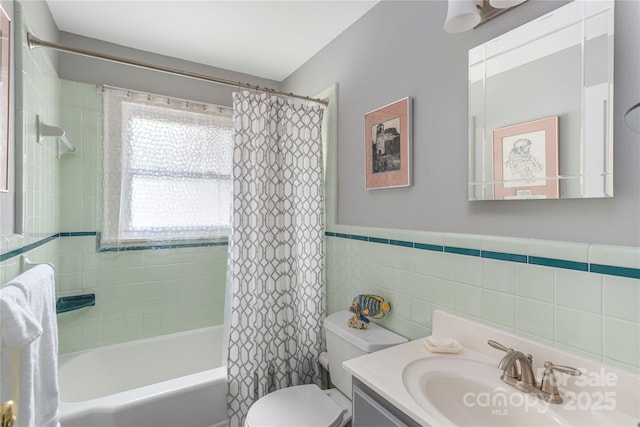 bathroom with vanity, wainscoting, shower / bath combination with curtain, toilet, and tile walls
