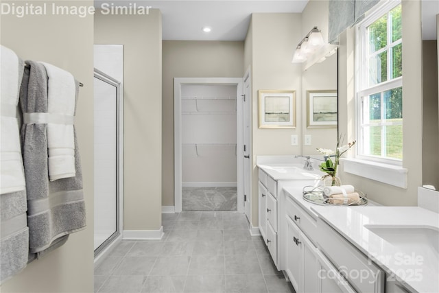 bathroom featuring a walk in closet, tile patterned flooring, vanity, baseboards, and a shower stall