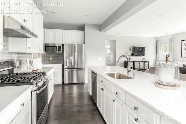 kitchen with open floor plan, under cabinet range hood, white cabinets, a sink, and appliances with stainless steel finishes