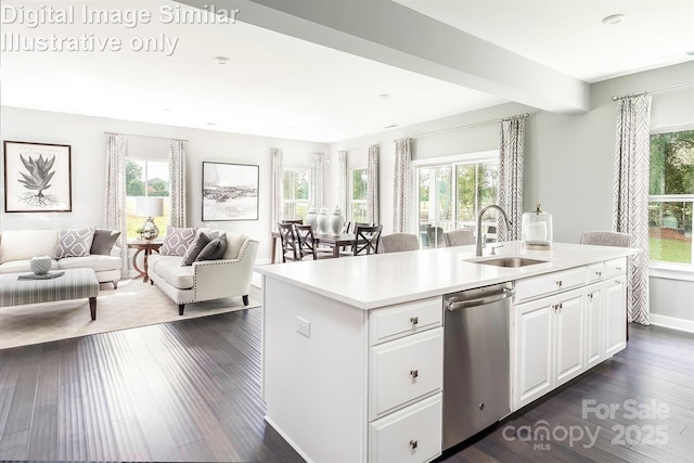 kitchen with stainless steel dishwasher, a sink, light countertops, open floor plan, and white cabinetry