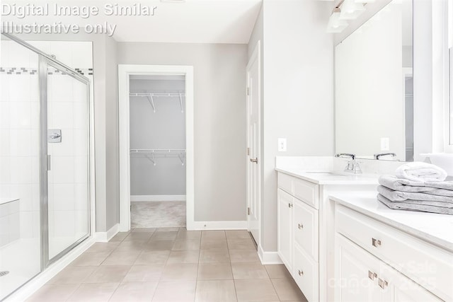 full bath with vanity, baseboards, a stall shower, and a spacious closet
