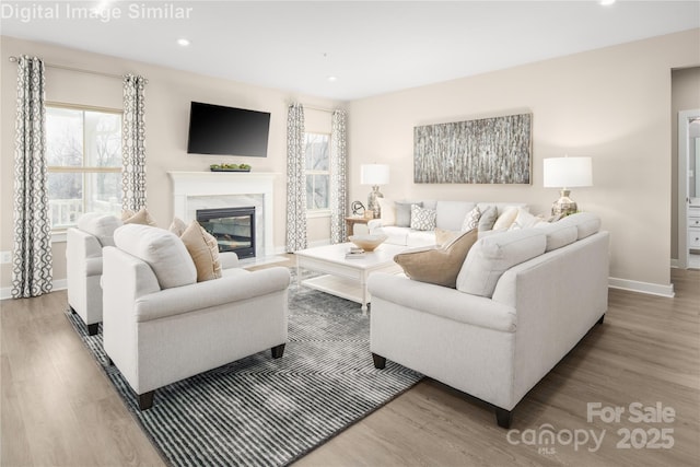 living room with a high end fireplace, baseboards, recessed lighting, and wood finished floors