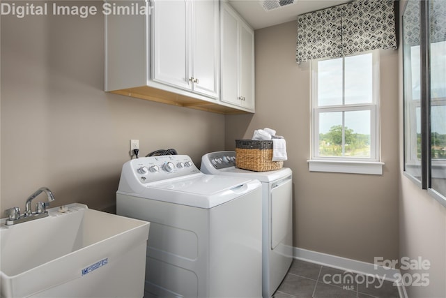 laundry area featuring baseboards, dark tile patterned floors, a sink, cabinet space, and independent washer and dryer