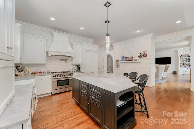 5400 Challisford Ln, Charlotte, NC 28226 - kitchen featuring high end stainless steel range oven, custom range hood, a kitchen breakfast bar, white cabinetry, and ornamental molding