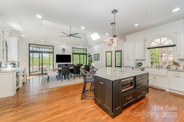 5400 Challisford Ln, Charlotte, NC 28226 - kitchen featuring white cabinetry, stainless steel microwave, light wood-style flooring, and a sink