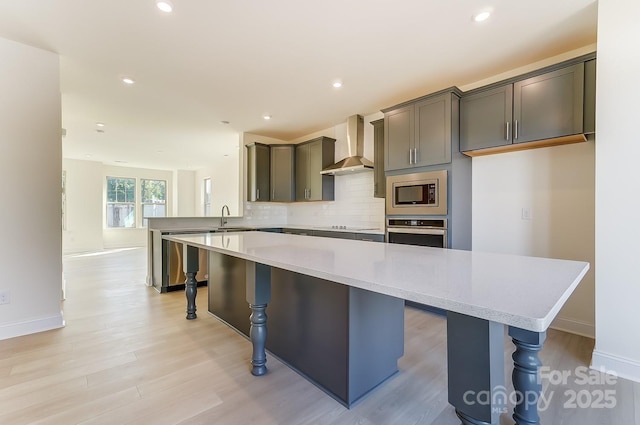 2907 W Trade St, Charlotte, NC 28208 - kitchen featuring light wood-style flooring, wall chimney exhaust hood, stainless steel appliances, a kitchen breakfast bar, and tasteful backsplash