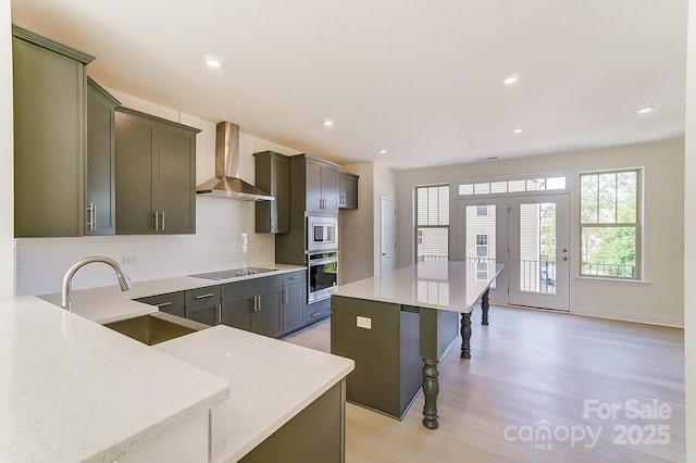 2907 W Trade St, Charlotte, NC 28208 - kitchen featuring a sink, appliances with stainless steel finishes, wall chimney exhaust hood, backsplash, and light wood-style floors