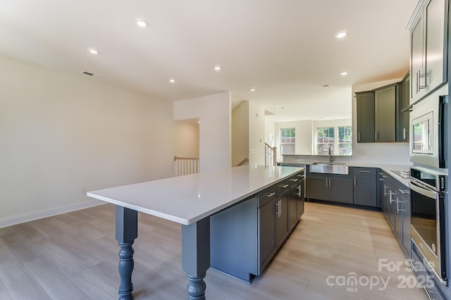 2907 W Trade St, Charlotte, NC 28208 - kitchen featuring light wood-style floors, appliances with stainless steel finishes, a center island, and a sink