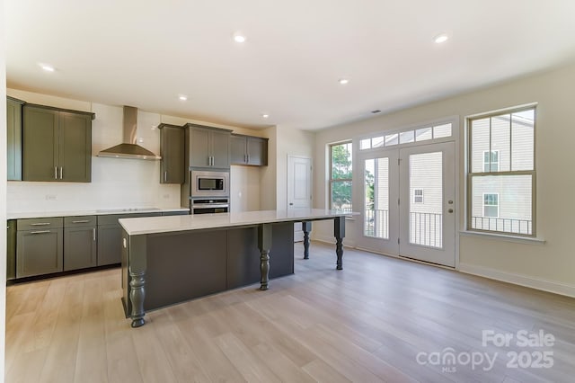 2907 W Trade St, Charlotte, NC 28208 - kitchen featuring light wood-style flooring, a breakfast bar, wall chimney range hood, stainless steel appliances, and tasteful backsplash