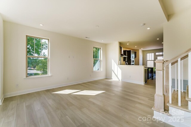 2907 W Trade St, Charlotte, NC 28208 - unfurnished living room with light wood finished floors, stairs, baseboards, and recessed lighting