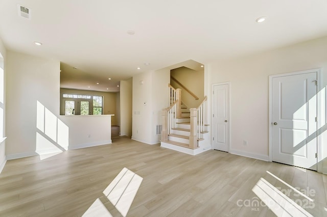 2907 W Trade St, Charlotte, NC 28208 - unfurnished living room with baseboards, stairway, light wood-style flooring, and visible vents