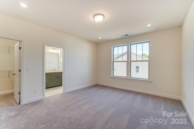 2907 W Trade St, Charlotte, NC 28208 - unfurnished bedroom with light colored carpet, visible vents, baseboards, and a walk in closet