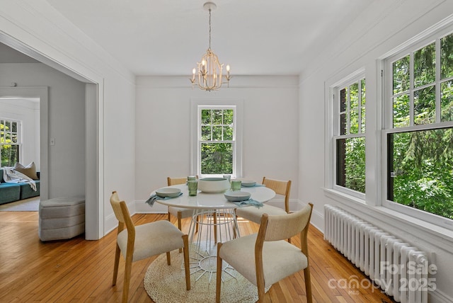 dining space with an inviting chandelier, light wood-type flooring, baseboards, and radiator heating unit