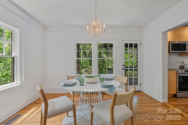 dining area with baseboards, an inviting chandelier, visible vents, and light wood-style flooring