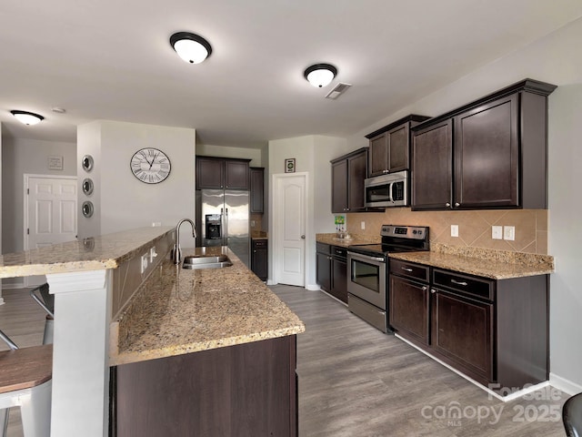 6541 Hasley Woods Dr, Huntersville, NC 28078 - kitchen featuring dark brown cabinetry, a sink, stainless steel appliances, wood finished floors, and backsplash