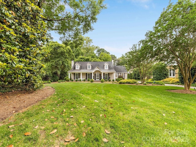 new england style home featuring a front yard and a chimney