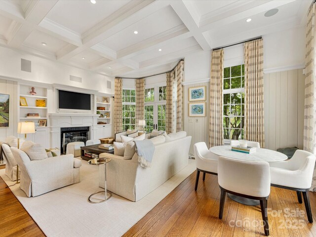 living room with coffered ceiling, wood-type flooring, beam ceiling, a glass covered fireplace, and recessed lighting