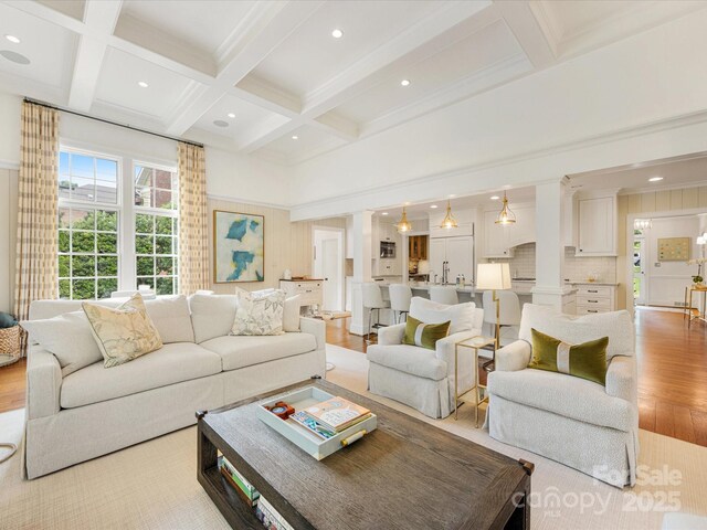 living room featuring light wood finished floors, beamed ceiling, coffered ceiling, recessed lighting, and crown molding