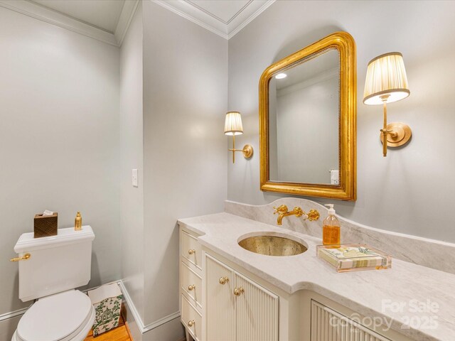 half bath with toilet, crown molding, and vanity