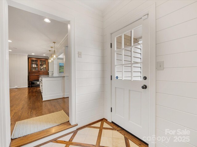 entryway featuring wood finished floors, recessed lighting, ornamental molding, and wood walls