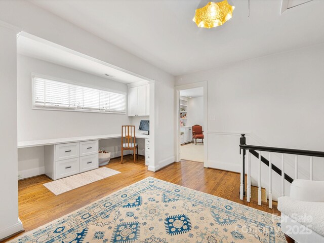 office featuring built in desk, light wood-style flooring, and baseboards