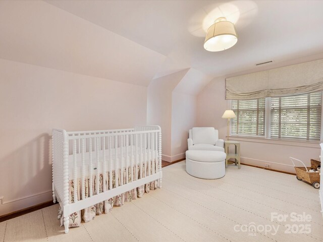 bedroom featuring lofted ceiling, baseboards, and a nursery area
