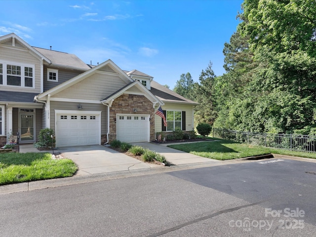 view of front facade featuring fence, an attached garage, a front lawn, stone siding, and concrete driveway