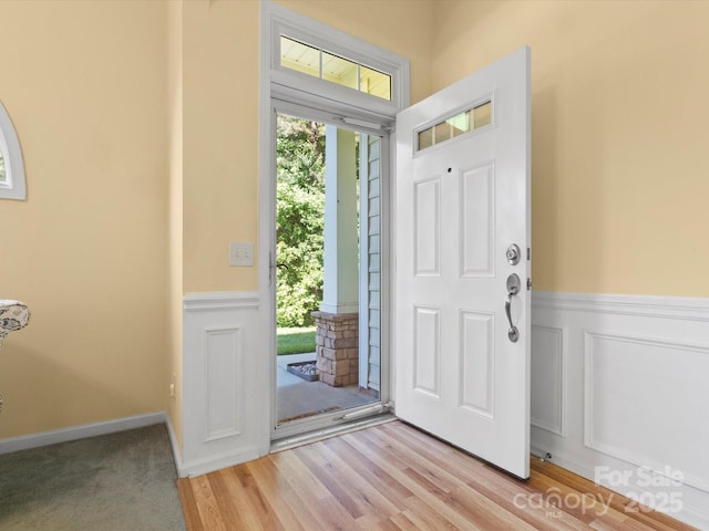 foyer with light wood-style flooring and wainscoting