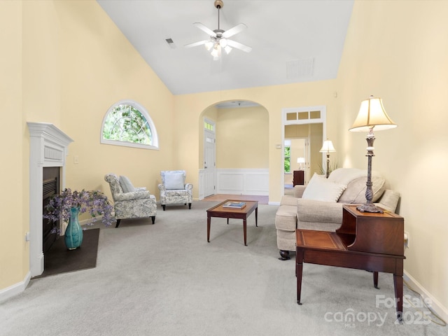 living area with arched walkways, high vaulted ceiling, light colored carpet, and a wealth of natural light