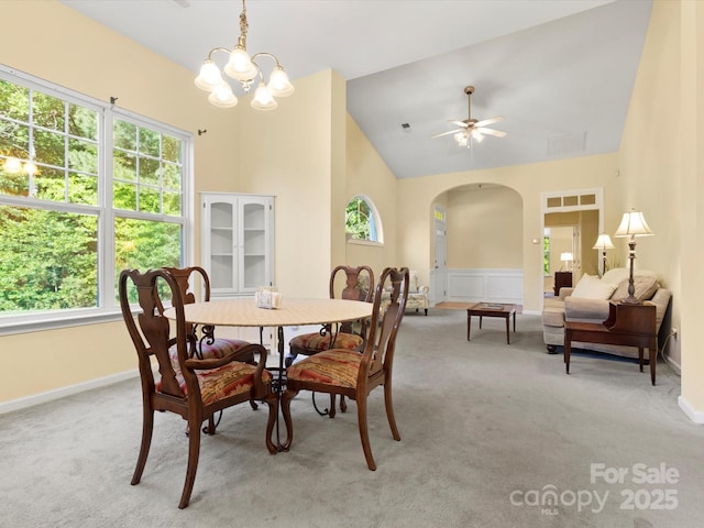 dining room featuring light colored carpet, arched walkways, and a healthy amount of sunlight