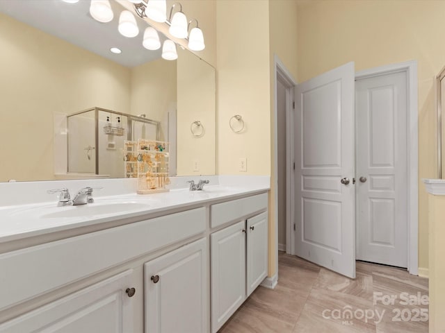 bathroom featuring double vanity, a sink, and a shower with shower door